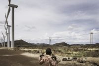 A boy at the Lake Turkana Wind Power installations, rows of turbines, powered by the natural jet stream of air called Turkana Corridorwind, blowing in off the Indian Ocean